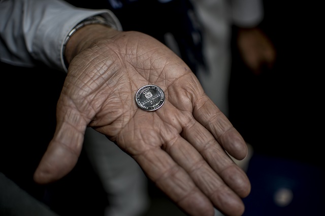 A man holds a new 50-Bolivar-coin in downtown Caracas on December 28, 2016. Venezuela took delivery on December 27 of its third load of new, bigger denomination banknotes, its central bank said, but there was no sign of them in circulation yet despite official promises and mounting public anxiety. Maduro's announcement that the 100-bolivar notes would suddenly no longer be legal tender provoked long lines of people trying to change them, and looting and rioting in some areas, resulting in four deaths. / AFP PHOTO / FEDERICO PARRA